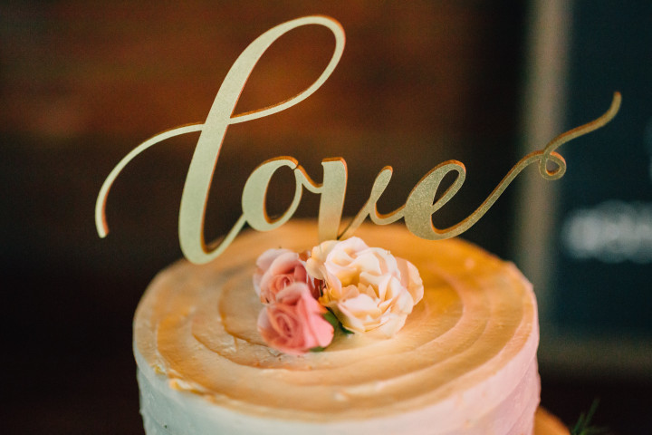 Simple tiered white wedding cake with gold love cake topper and pink flowers | EntertainingLife.com